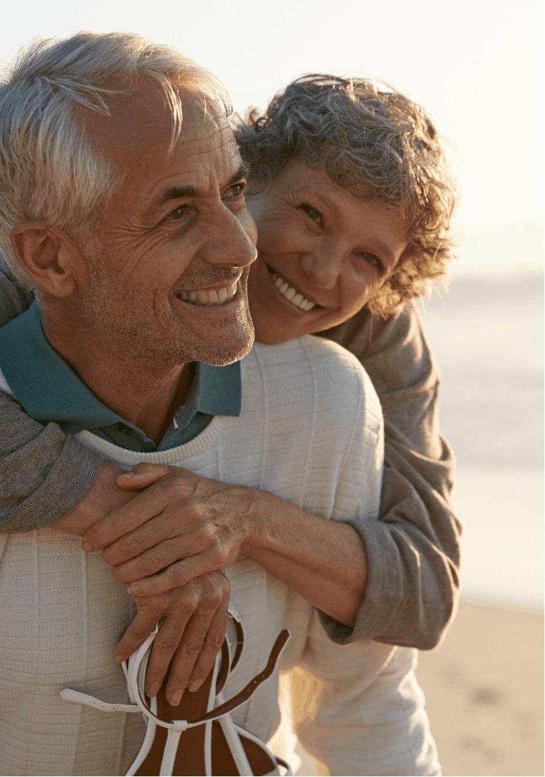 Photo of an older couple holding each other at the beach