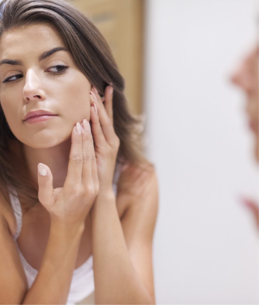 Woman inspecting her face in the mirror