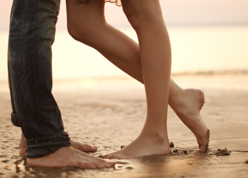 Close-up on a woman's and man's legs at the beach