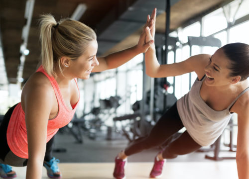 Two women high five at the gym