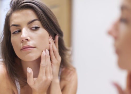 Woman checking for pimples in the mirror