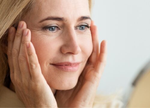 Photo of a middle age woman checking out her skin in a mirror